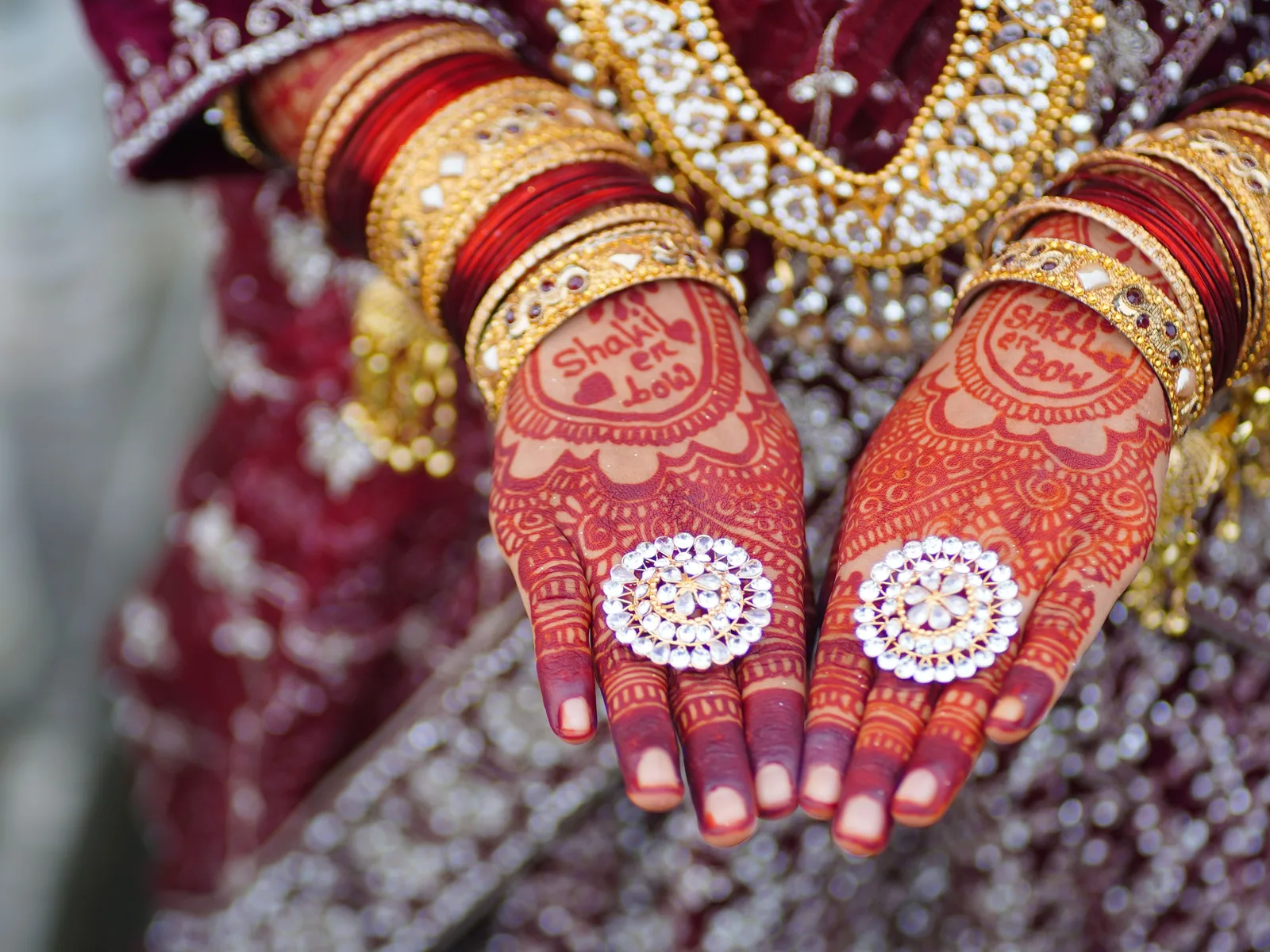 Bridal hands with rings, kundan bangles and detailed mehndi in soft directional light