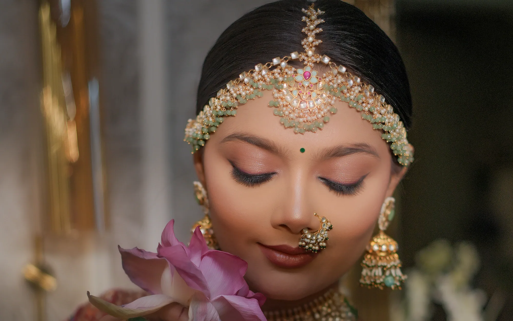 Bride styled by Brijal's — The Bridal Studio, wearing a kundan maang tikka, emerald necklace and a deep red embroidered lehenga